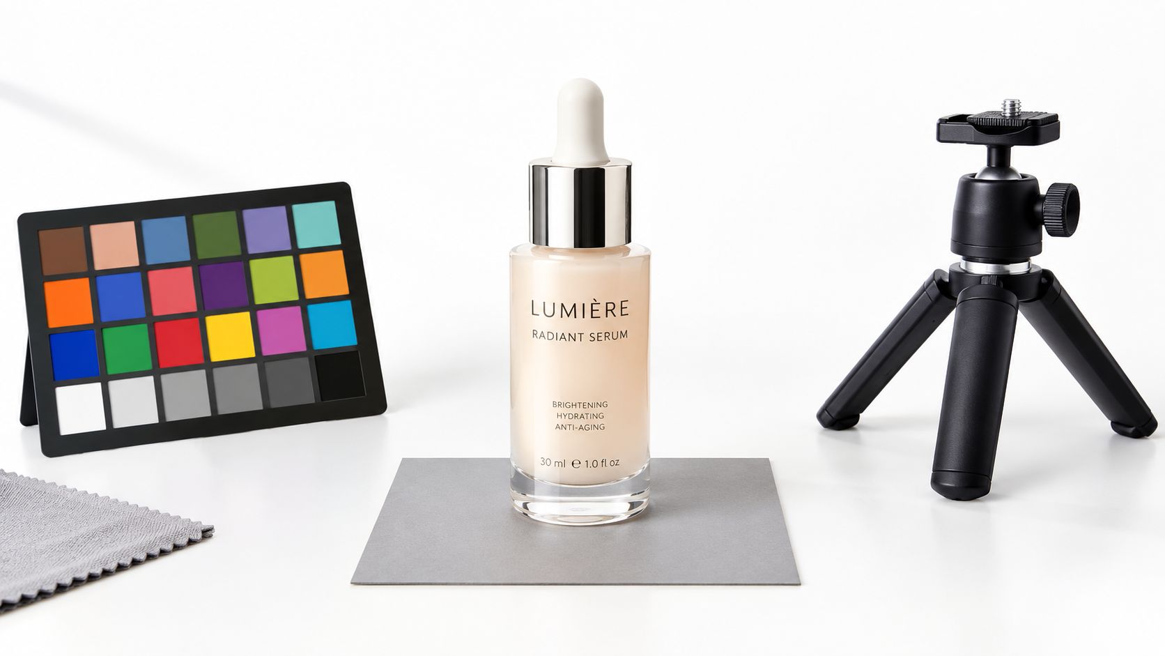 A professional product photography setup featuring a serum bottle, a color checker, and a small tripod.